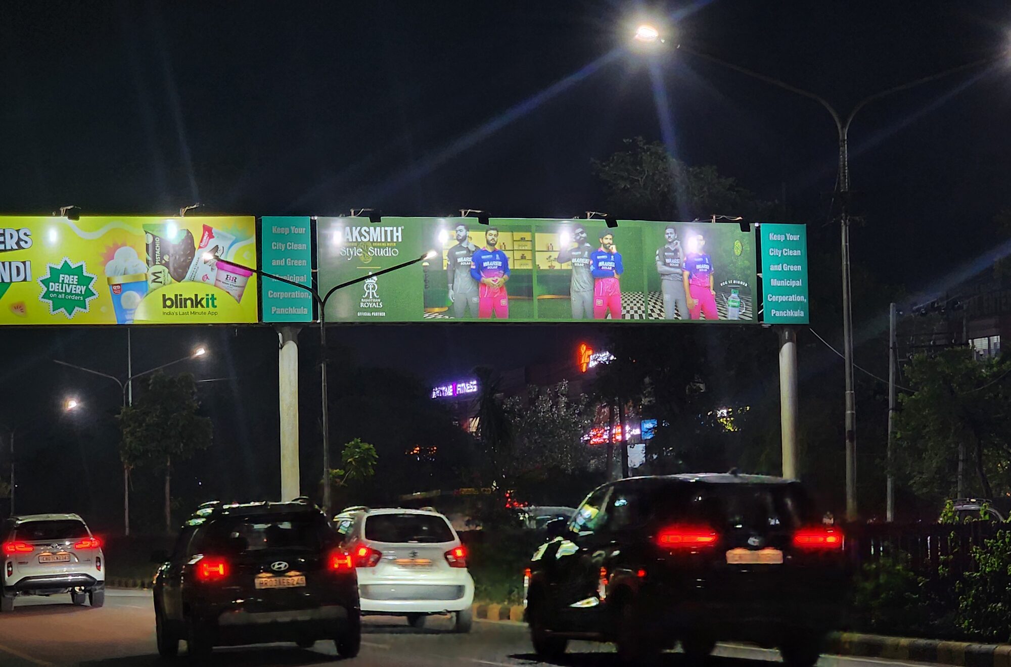 A lit advertising gantry over a Panchkula road at night